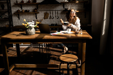 Beautiful young woman have breakfast while working on laptop at the kitchen 