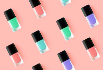 Fototapeta na wymiar Pattern from nail polish glass bottles on pink background. Mockup pink, blue, mint green and purple colors nail polishes fashion beauty products. Creative trendy flat lay, top view