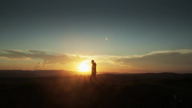 Man in silhouette walking in slow motion outdoors in the sunset