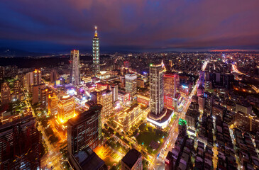 Aerial skyline of Downtown Taipei at night, the vibrant capital city of Taiwan, with towers standing out among modern skyscrapers in Xinyi Commercial District and city lights dazzling in the dark