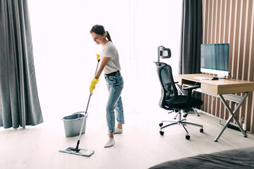 Fototapeta na wymiar Young pretty woman mopping the floor of living room