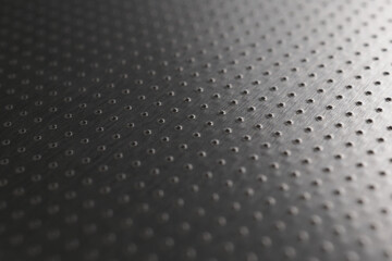 Perforated aluminum surface with many holes. Their ranks go into the distance and form a perspective. Industrial dark gray metal background or wallpaper. Macro