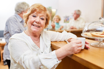 Fröhliche Seniorin beim Espresso trinken im Seniorencafe im Altenheim
