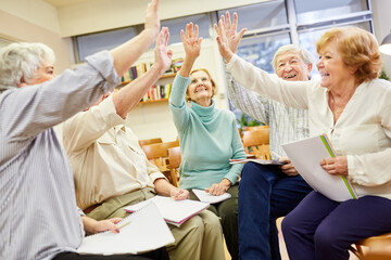 Gruppe vitaler Senioren macht High Five Übung für Interaktion und Zusammenhalt