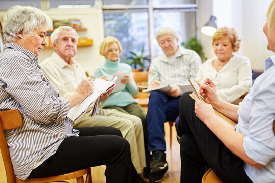 Gruppe Senioren mit Zeichenblock beim Malen und Zeichnen in einer Maltherapie