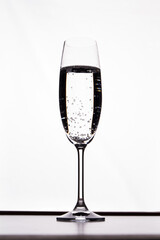 Glass of transparent alcoholic cocktail in a glass cup. Champagne with bubbles over white background.