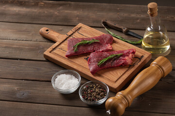 raw beef steaks on wooden board with ingredients