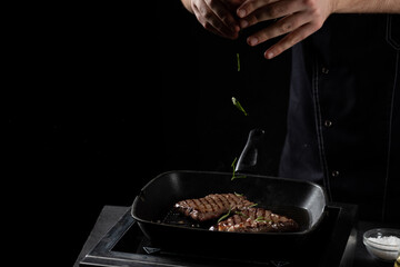 the chef sprinkles beef steak in a frying pan