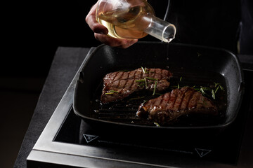 the chef pours butter on a beef steak in a frying pan