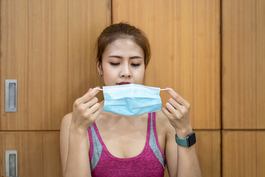 Portrait Of Asian Young Fitness Female Putting On Medical Face Mask At Sport Gym.  Happy Sports Woman Wearing Protective Mask.