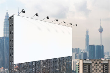 Obraz premium Blank white road billboard with KL cityscape background at day time. Street advertising poster, mock up, 3D rendering. Side view. The concept of marketing communication to promote or sell idea.