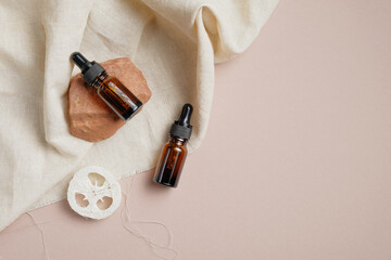 Essential oil bottles and loofah on brown background with beige fabric. Body treatment concept....