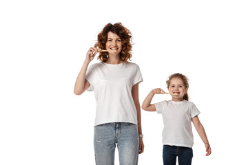 cheerful mother and daughter brushing teeth isolated on white