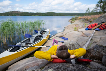 Young caucasian woman resting by the lake after kayaking.