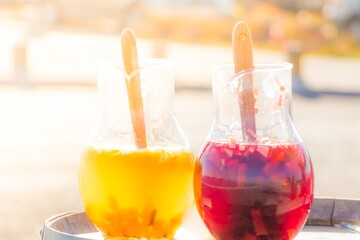 Yellow red big bowls of punch at vacation holiday bar. Fresh cool juicy orange pineapple juice and wine sangria in sunny summer. Tropical refreshment cocktail drink at holiday beach party