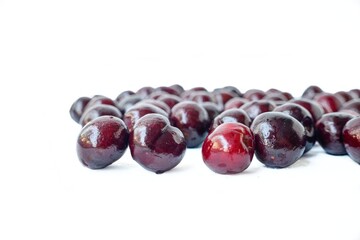 Scattered red cherry on a white background with drops of water.