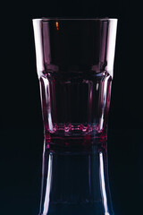 Glass for drinks on a black background. Transparent empty glass on reflection surface.
