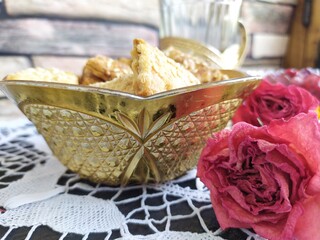 Still life a gilded bowl of cookies a bowl of raspberry jam white sugar on a plate a glass in a cup holder on the kitchen table