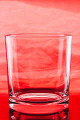 Small glass on red background.Transparent empty glass for alcoholic beverages.