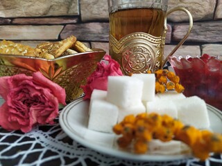 Still life a gilded bowl of cookies a bowl of raspberry jam white sugar on a plate a glass in a cup holder on the kitchen table