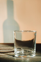 Empty small shot glass and shadow of bottle. Concept of drinking in a bar.