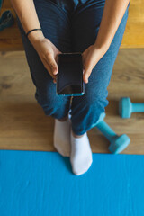 Fitness workout mobile app concept. Detail of sporty female hands holding smartphone.
