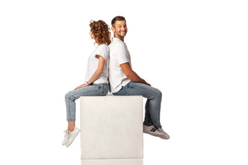 happy couple smiling and sitting on cube on white