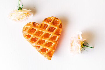 Heart shaped cookie with jam and  with two fine pink roses on a white background. heart-shaped cake on a white and bright background. Valentines Day