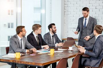 leadership and business concept. business team in modern office sit having active discussion of business ideas together, wearing tuxedo, formalwear