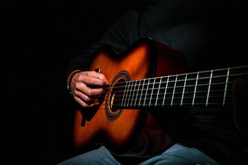 Closeup shot of a musician playing guitar under the lights