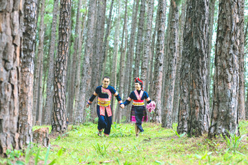 Couple hmongs holding hands and running in the pine wood, Man and woman in Hmong clothes