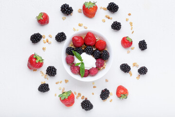 Fruit salad bowl with strawberry, blueberry, raspberry and yogurt on white background. Flat lay, top view summer healthy concept.