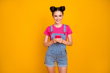 Portrait of her she nice-looking attractive lovely cheerful cheery girl using modern technology cell browsing web isolated on bright vivid shine vibrant yellow color background