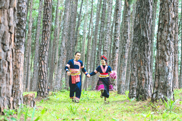 Couple hmongs holding hands and running in the pine wood, Man and woman in Hmong clothes