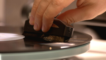 Close-up view of hand which holding a gramophone's needle. Beautiful retro music.