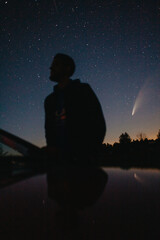 Young man on the background of the starry sky and comet NEOWISE. Comet C / 2020 F3 NEOWISE Observation