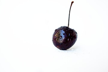 Juicy washed ripe black cherry on a white background with drops of water.