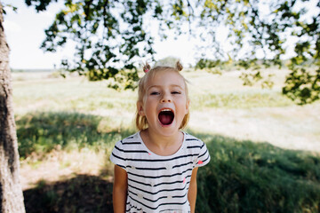 Little baby girl screaming in summer park outdoors