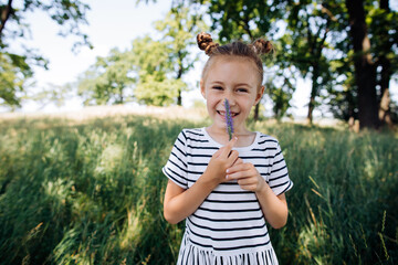 Little girl with a blue flower in her hands in a summer park. Children's vacation