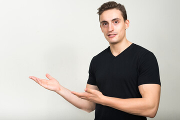 Portrait of happy young handsome man showing something