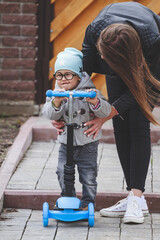 Little boy  with his mother learn to ride a scooter