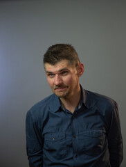 concentrated man with bad vision looks straight posing for photo shoot against grey studio background close view