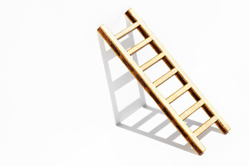 Small wooden ladder leaning against a white wall casting shadows.
