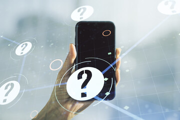 Creative abstract question mark hologram and hand with mobile phone on background, future technology concept. Multi exposure