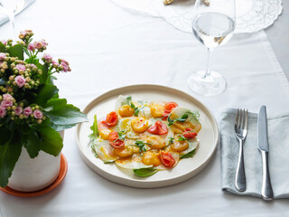 Scallop with ginger and micro greens. Bright seafood platter decorated with stalks of green peas. Served on a white ceramic plate. White tablecloth. Beautiful table setting. Fish restaurant.