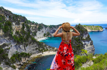 Happy traveller woman in red dress enjoys her tropical beach vacation