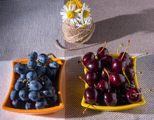 Saucers with cherry grapes, a bouquet of flowers on the table