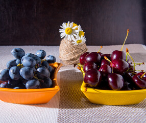 Saucers with cherry grapes, a bouquet of flowers on the table