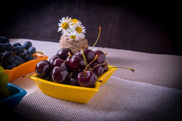 Saucers with cherry grapes, a bouquet of flowers on the table