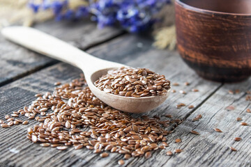 Flax seeds lie on old boards and in a spoon on a wooden table.